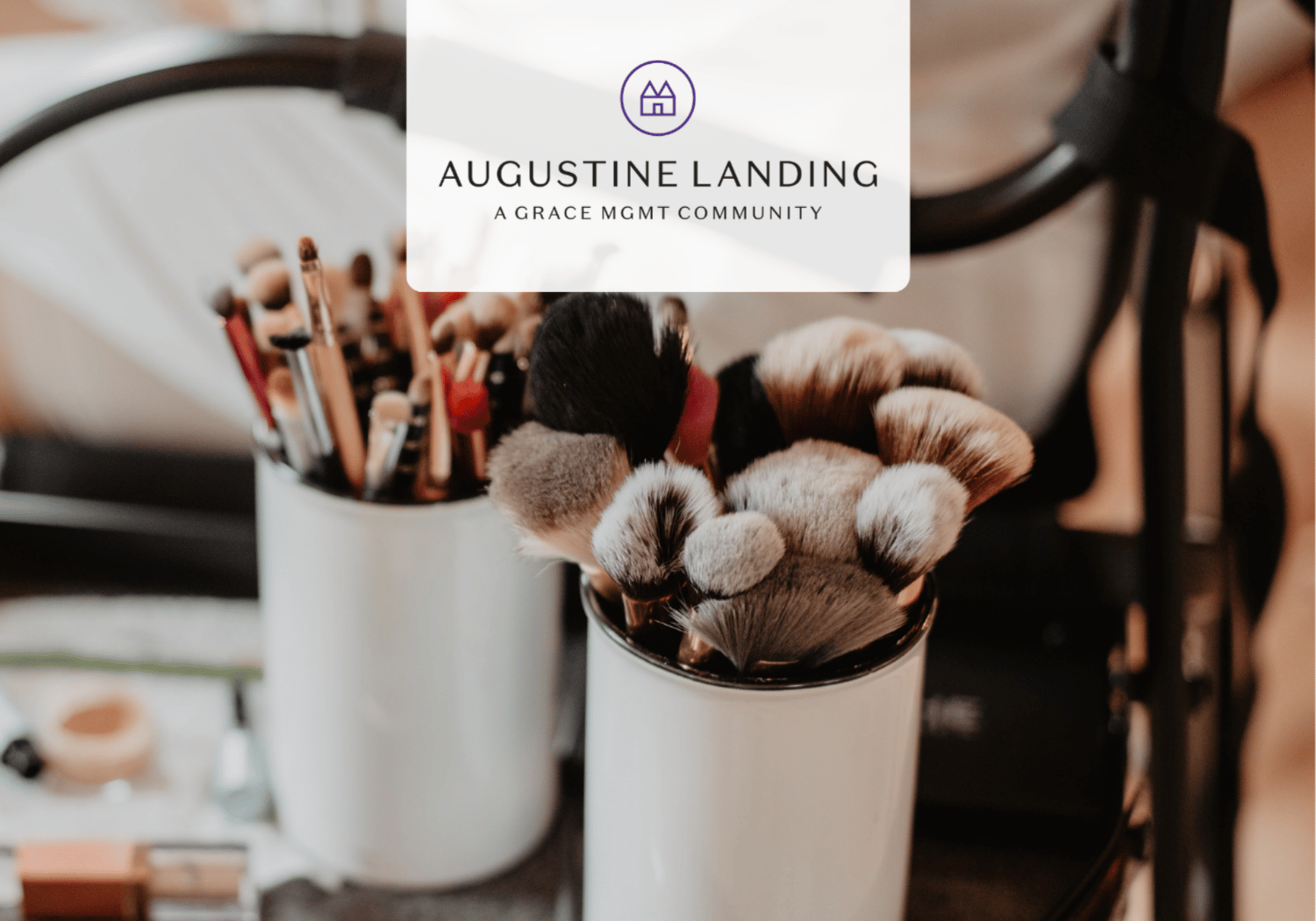Close-up of makeup brushes in white cups on a vanity with a blurred background and a logo overlay reading Augustine Landing.