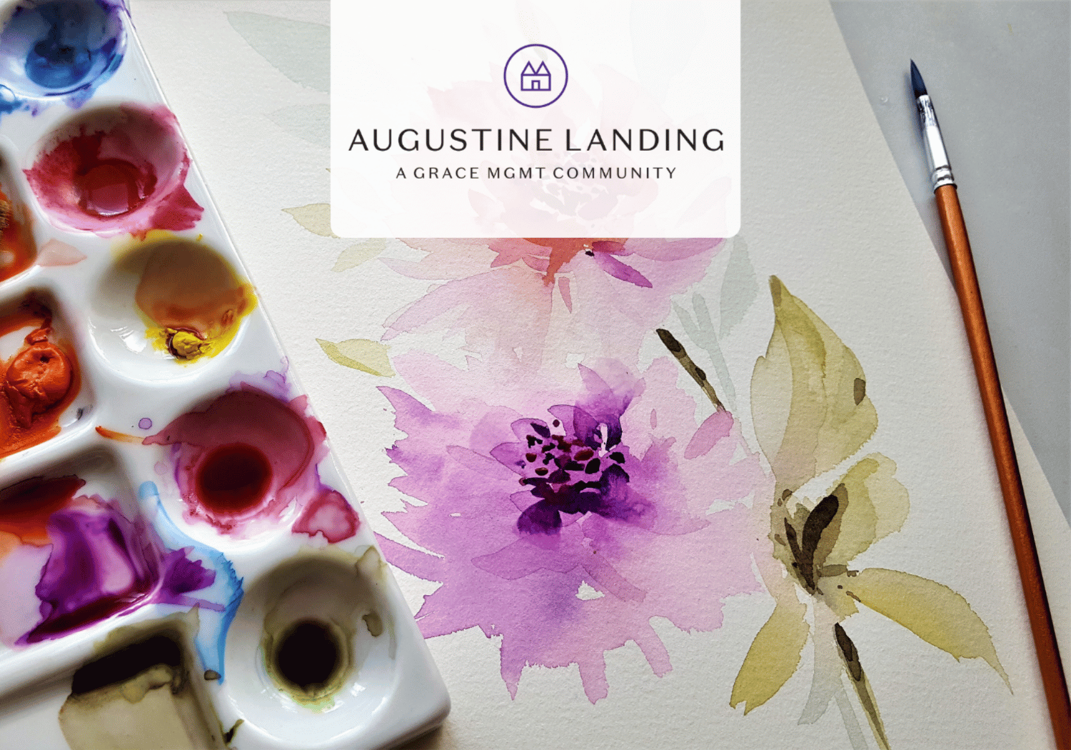 Watercolor palette and brush beside a pink floral painting with the Augustine Landing branding overlay at the top center.