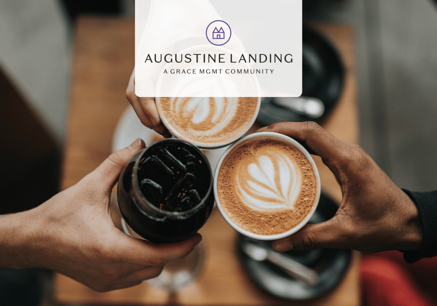Top-down view of three coffee cups being toasted together: two lattes with latte art and a glass of iced coffee, with a branding overlay in the center